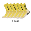 Sechs Paar gelb-cremefarbener sportlicher rutschfester Socken in einer Reihe.