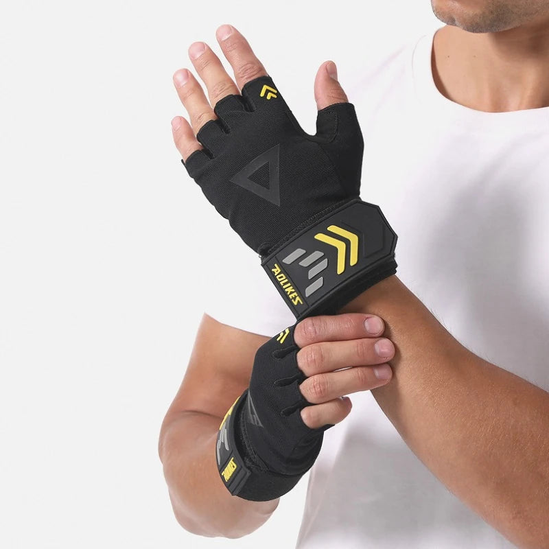 A hand wearing a black weightlifting grip with yellow accents, shown against a white shirt.