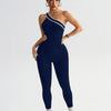 A model wearing a navy blue seamless yoga jumpsuit with a white stripe detail.