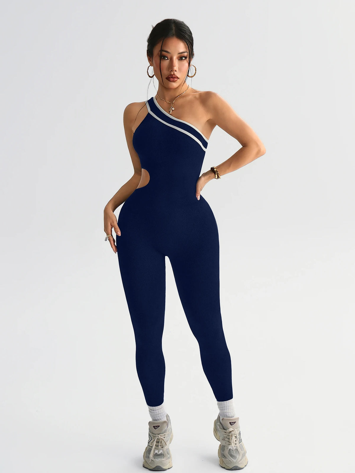 A model wearing a navy blue seamless yoga jumpsuit with a white stripe detail.