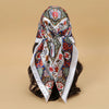 An elegant satin square scarf featuring intricate floral patterns in blue, red, and green for hijab or hair