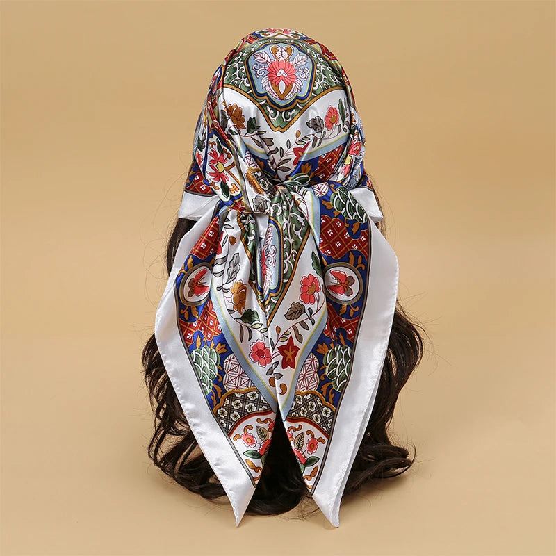 An elegant satin square scarf featuring intricate floral patterns in blue, red, and green for hijab or hair