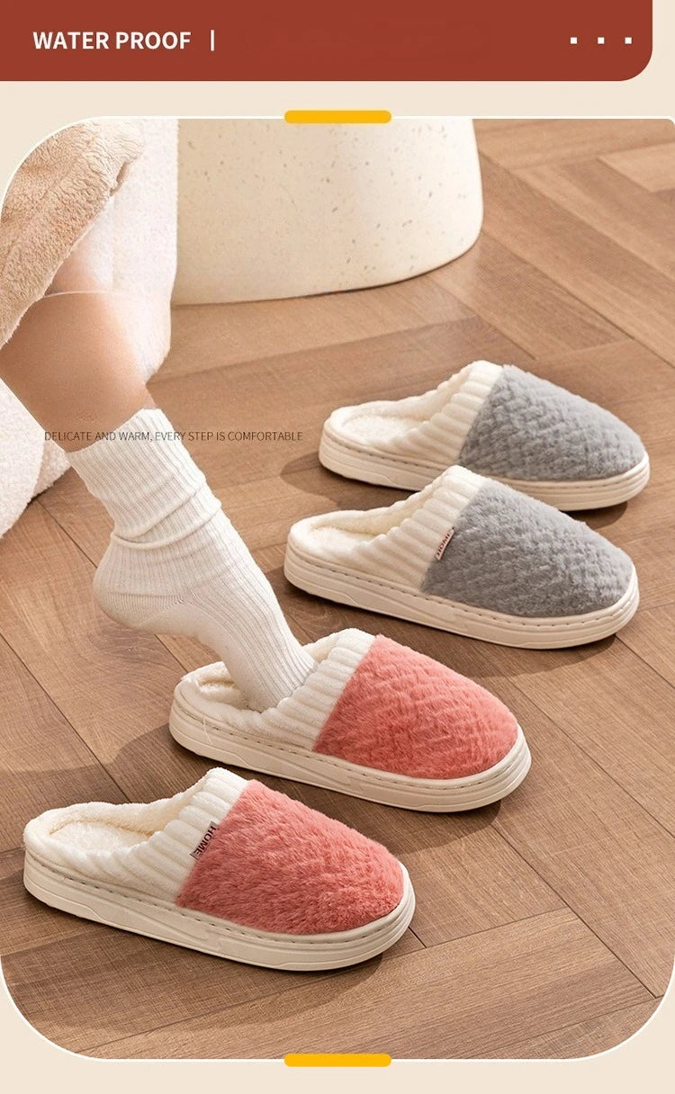 A close-up of water-proof plush fleece slippers in white, gray, and pink colors resting on a wooden floor.