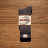 A pair of dark gray tube socks with a white label featuring the word Quality