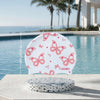 White silicone swimming cap with pink butterfly print resting on a concrete surface by a pool.