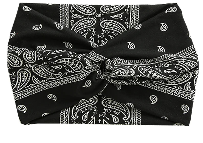 Black and white paisley patterned women's elastic sports headband tied in a bow