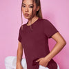 A woman wearing a maroon breathable summer yoga and fitness t-shirt in a studio setting.