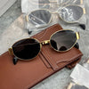 A pair of classic oval metal sunglasses with gold-toned frames and dark lenses resting on a brown leather wallet.