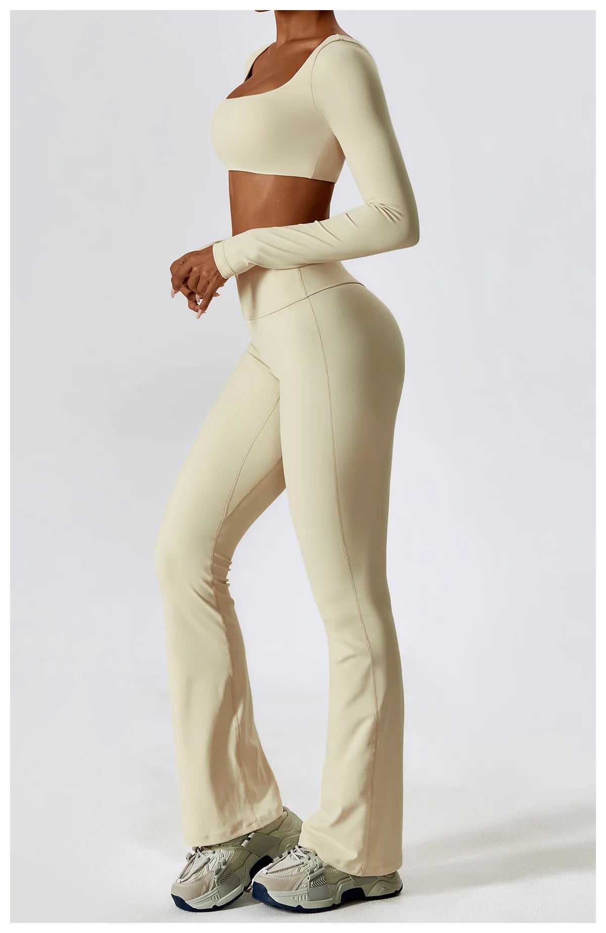 A woman models a beige performance tracksuit set consisting of a cropped long-sleeve top and matching high-waisted pants.