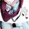 A maroon foldable travel duffel bag is shown being carried in a light blue fabric bag.