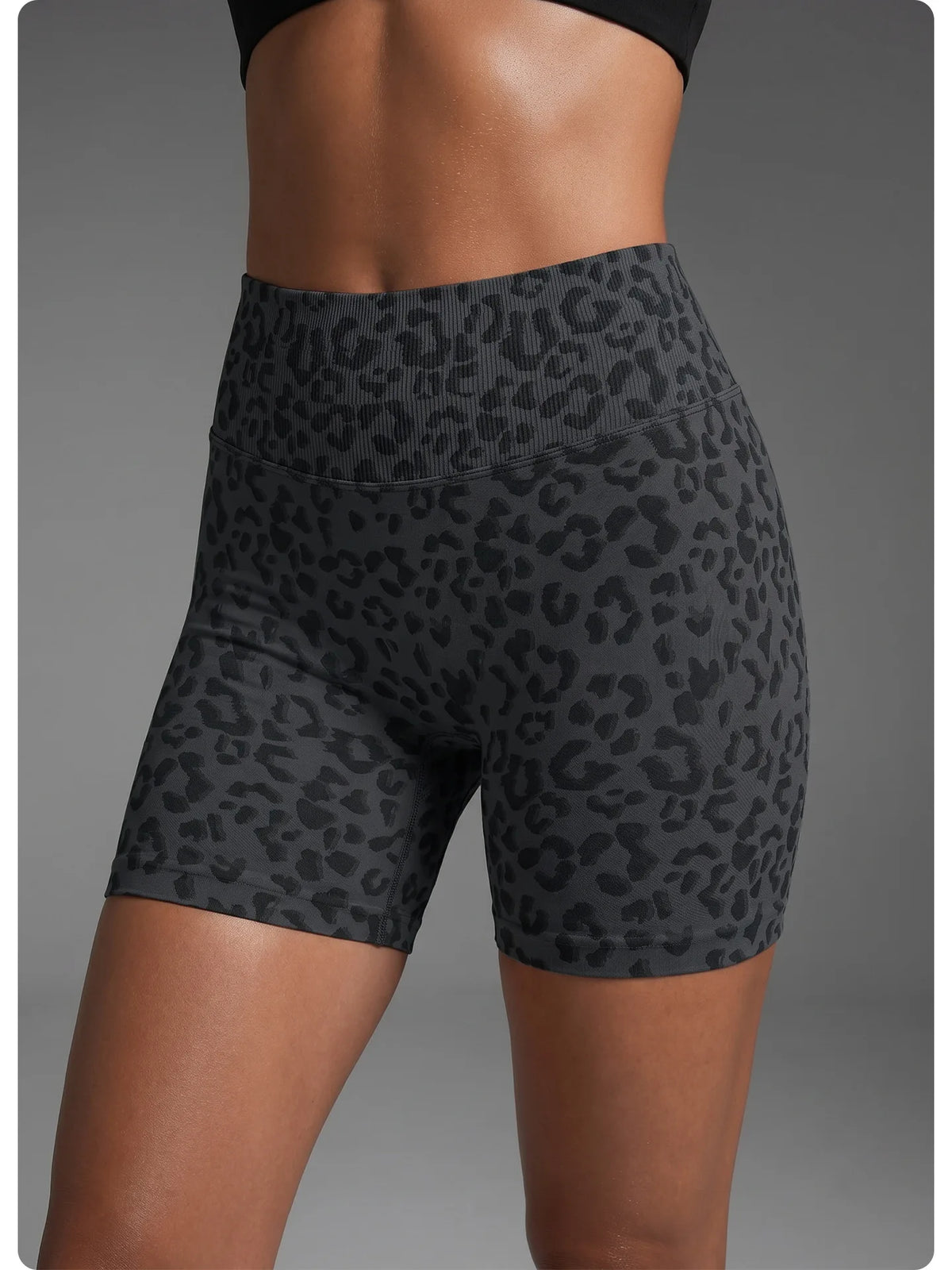 Un mannequin porte des shorts de yoga taille haute à imprimé léopard gris foncé.