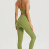 A woman wearing a lime green halter neck sports bra top and matching leggings poses against a light gray background.