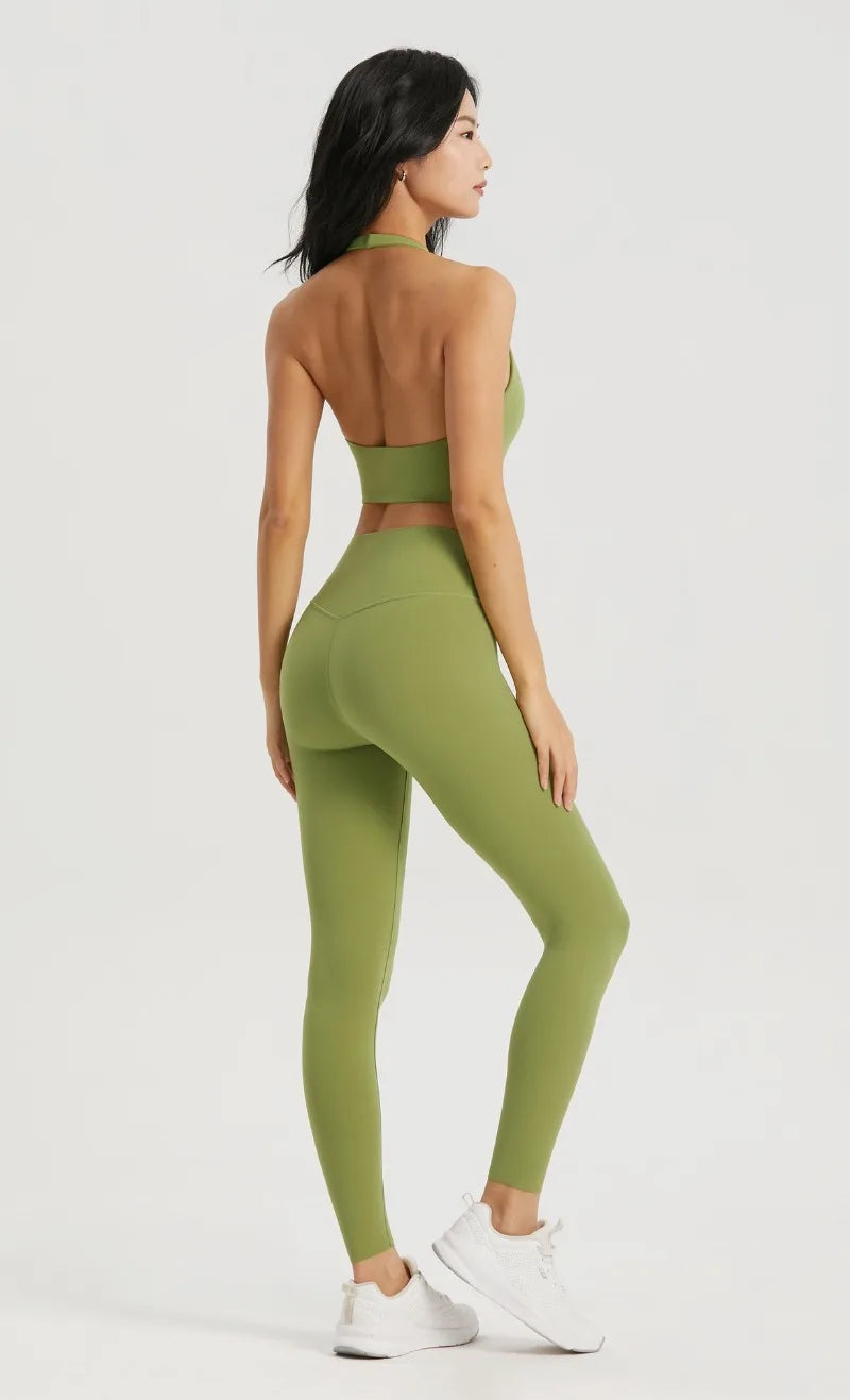 A woman wearing a lime green halter neck sports bra top and matching leggings poses against a light gray background.