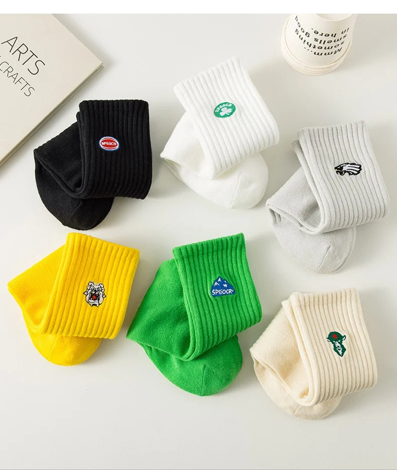 A collection of men's athletic embroidered crew socks in various colors including black, white, gray, yellow, and green.