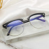 A pair of purple-framed computer glasses with clear lenses resting on a glass surface.