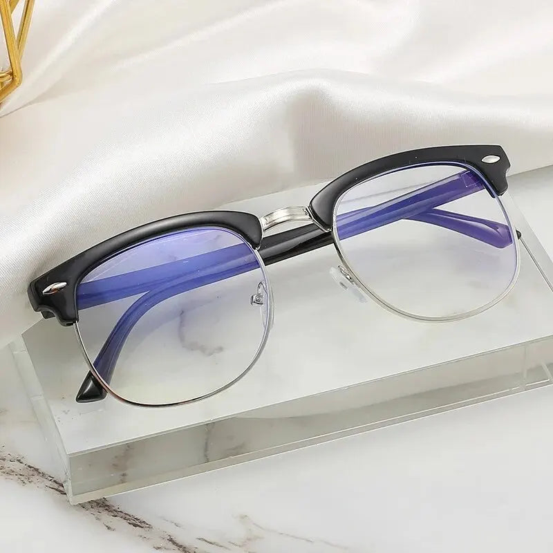 A pair of purple-framed computer glasses with clear lenses resting on a glass surface.