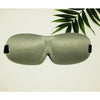 A smooth, olive green memory foam sleep mask is shown against a light background with a green leaf in the upper right corner.