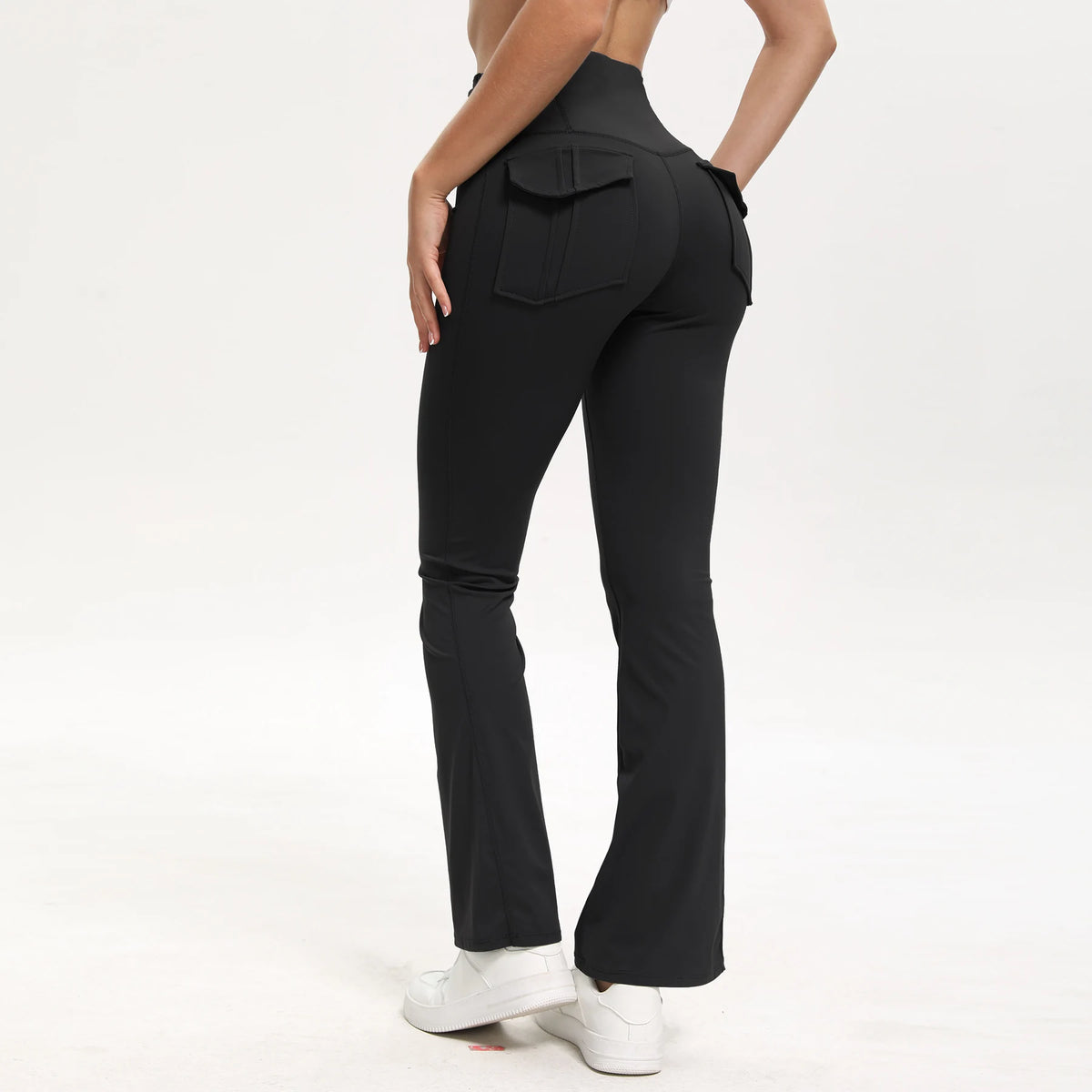 A person wearing black high-waisted flared yoga leggings with a front pocket detail.