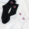 A pair of black and white crew socks with red numbers 23 on the foot.