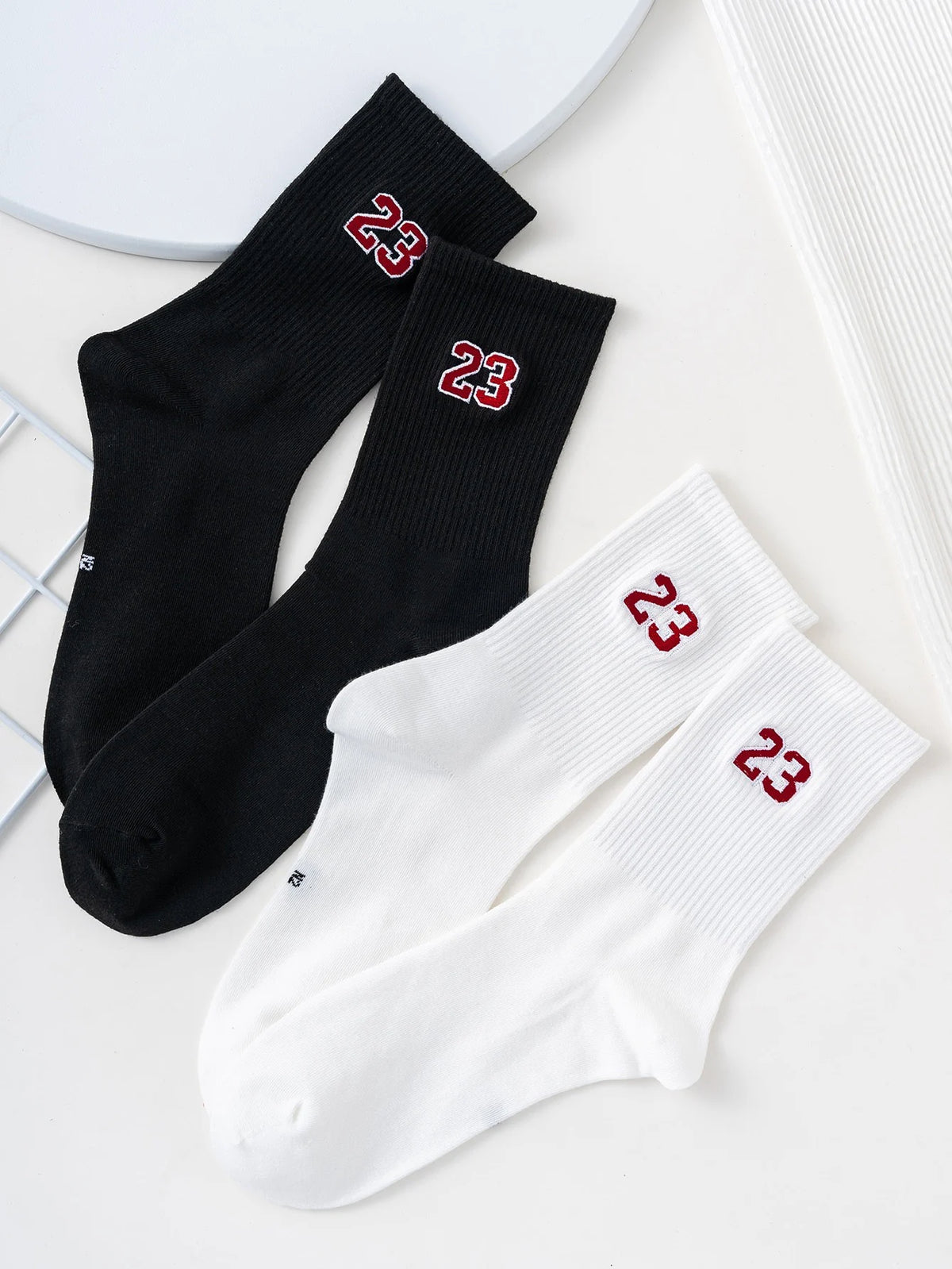 A pair of black and white crew socks with red numbers 23 on the foot.