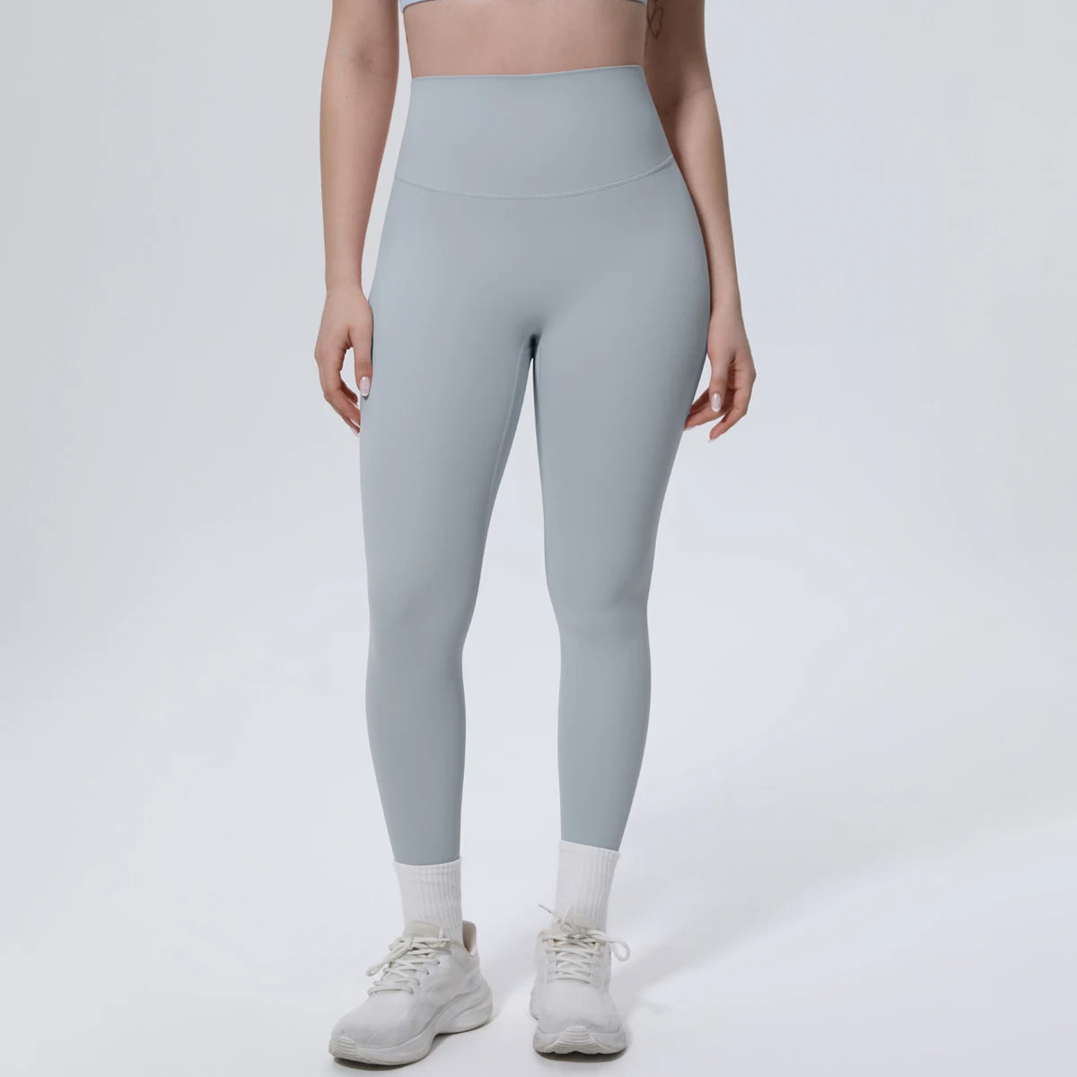 A model wearing light blue high-waisted quick-drying yoga and fitness leggings with white socks and white athletic shoes.
