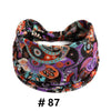 A close-up of a patterned boho print cotton headband featuring purple, orange, and teal floral designs.