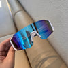 A hand holds a pair of blue-tinted cycling sunglasses against a light background.