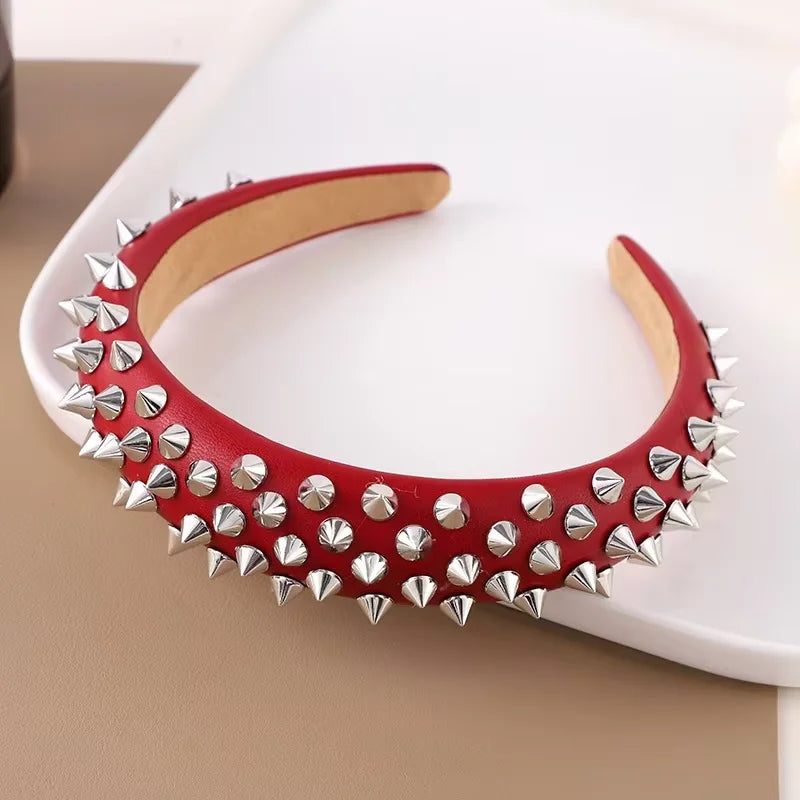 Bandeau en cuir rouge punk grunge avec trous et épingles argentées sur une surface blanche