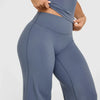 A person is wearing a fitted, dark blue high-waist yoga pant with a side cutout.