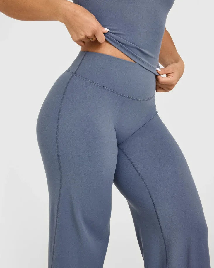 A person is wearing a fitted, dark blue high-waist yoga pant with a side cutout.