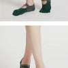 A pair of dark green silicone yoga socks with a gray accent, shown on a person's feet.