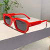 A pair of bright red classic rectangle sunglasses resting on a white surface.