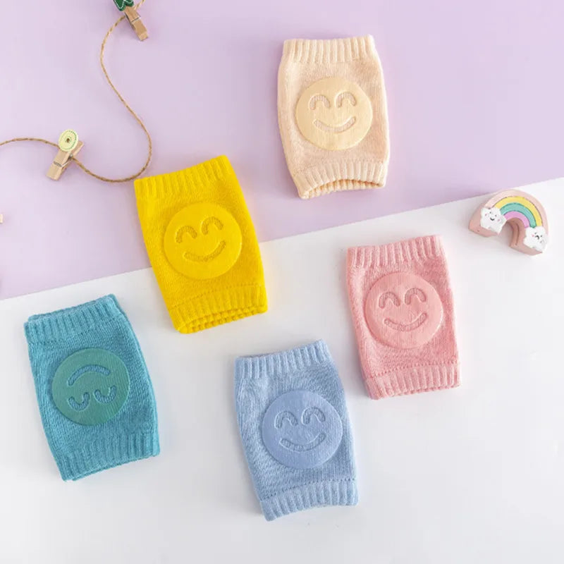 Eine Sammlung weicher elastischer Wadenwärmer in Gelb, Pink und Blau mit lächelnden Gesichtern auf einer weißen Oberfläche.