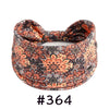 A close-up of an orange and black patterned boho knotted cotton headband.