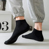 A pair of black thin ankle socks being worn on a person's foot.