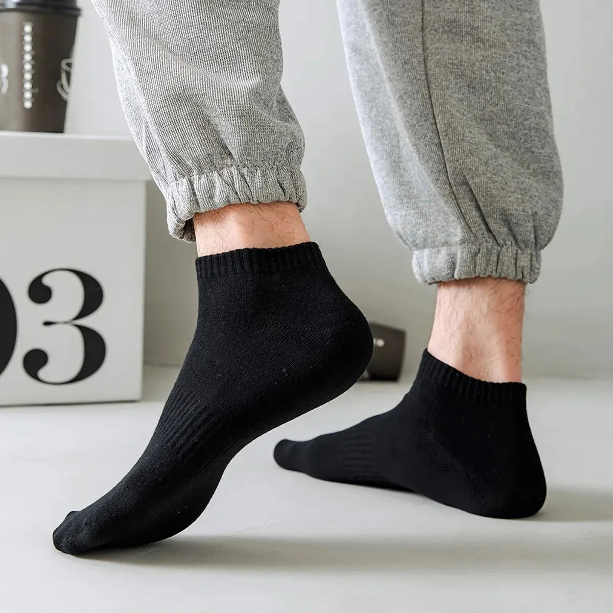 A pair of black thin ankle socks being worn on a person's foot.