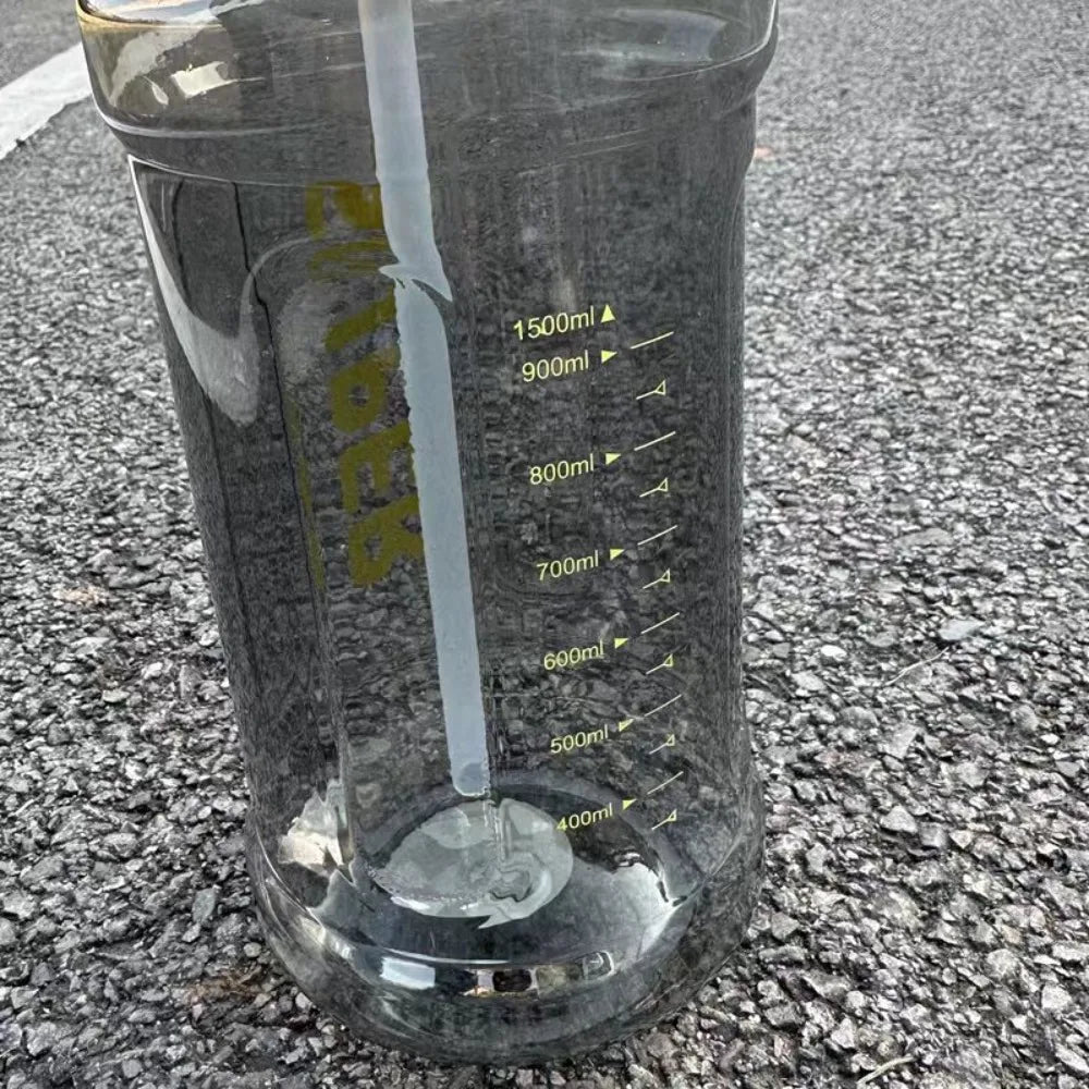 A clear insulated sports water bottle filled with water, resting on an asphalt surface.
