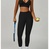 Eine Frau modelliert ein schwarzes, nahtloses Sport-Yoga-Set aus Crop-Top und Leggings und hält einen limettengrünen Ball.