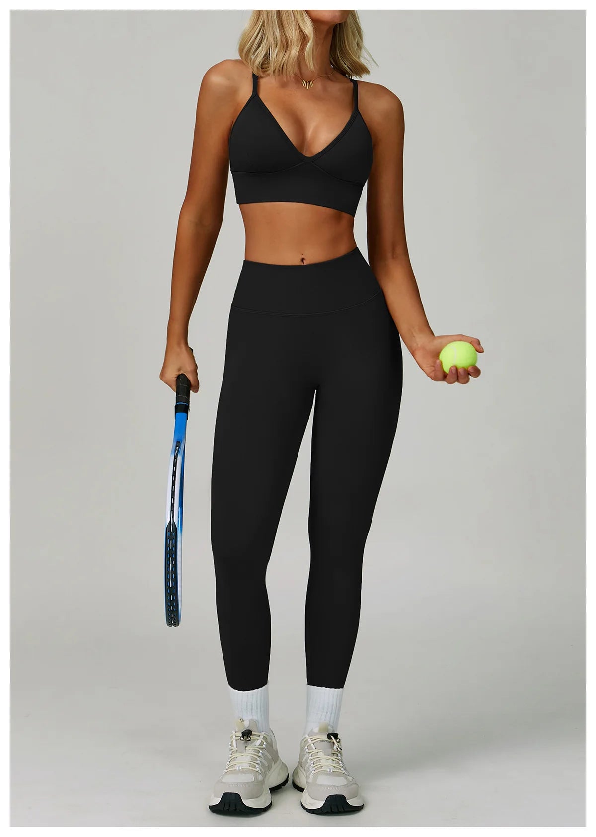 Eine Frau modelliert ein schwarzes, nahtloses Sport-Yoga-Set aus Crop-Top und Leggings und hält einen limettengrünen Ball.
