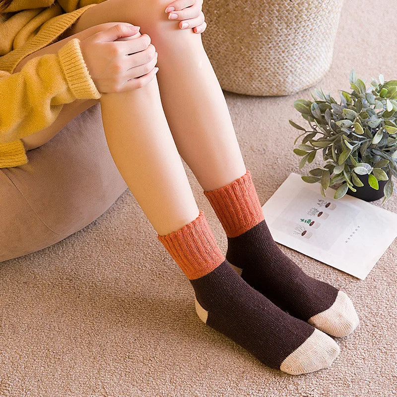 A close-up of a person's legs and feet wearing knitted crew socks in shades of orange, brown, and beige.
