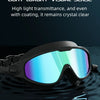 A pair of black swimming goggles with blue-tinted lenses floating on dark water.