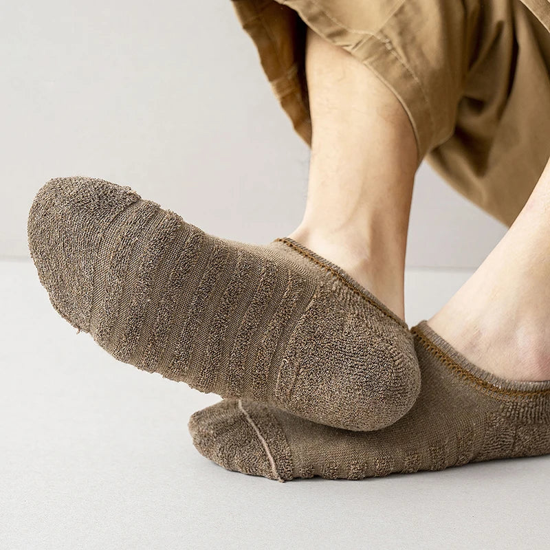 A close-up of brown men's cotton crew socks being worn on a foot.