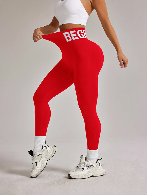 A woman wearing red high-waisted seamless yoga leggings and a white crop top, standing on a light gray floor.