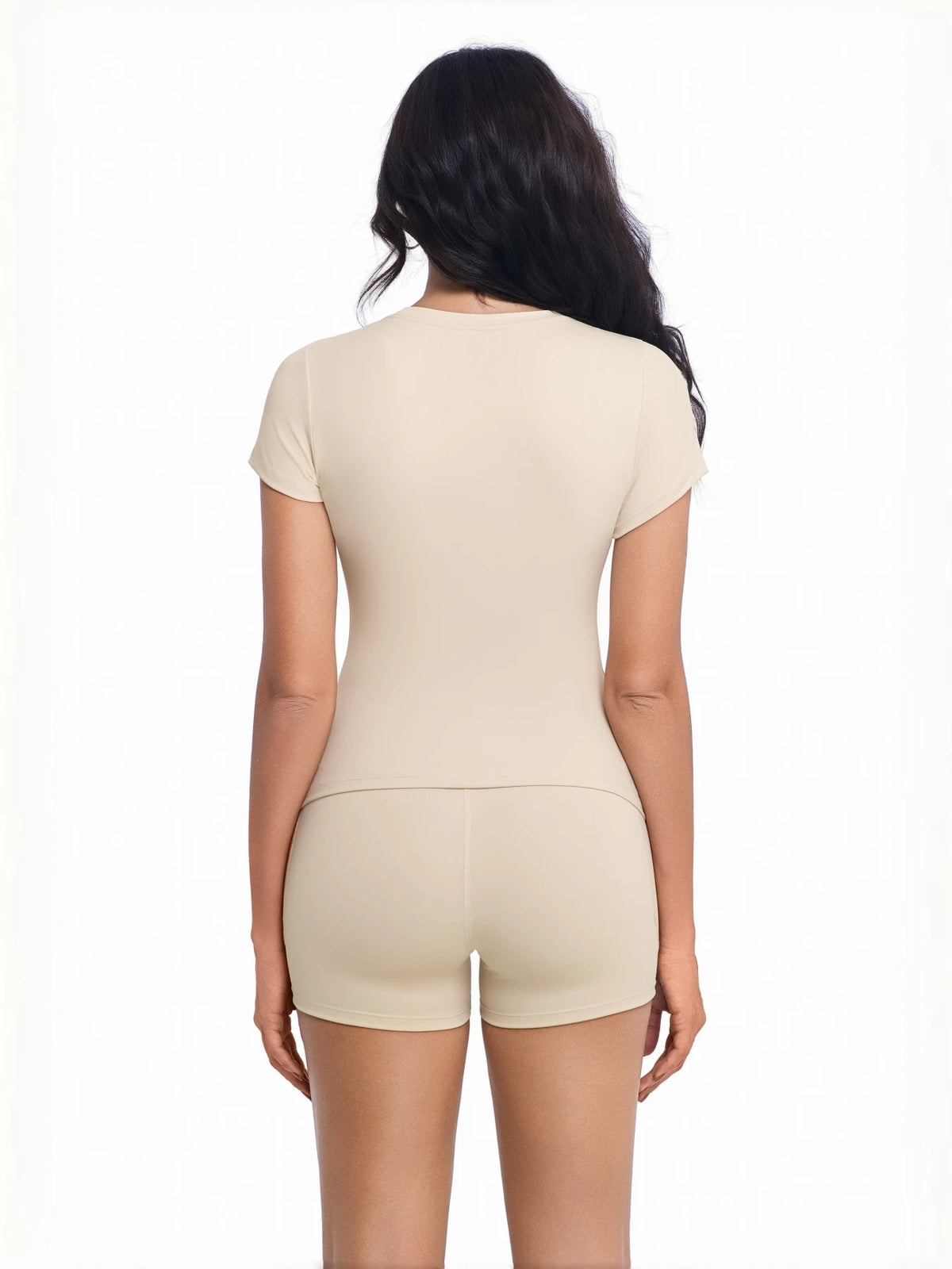 A woman wearing a beige two-piece workout set top and shorts from the back.