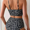 Una mujer modela un bikini de dos piezas con estampado floral negro de cintura alta desde la espalda.