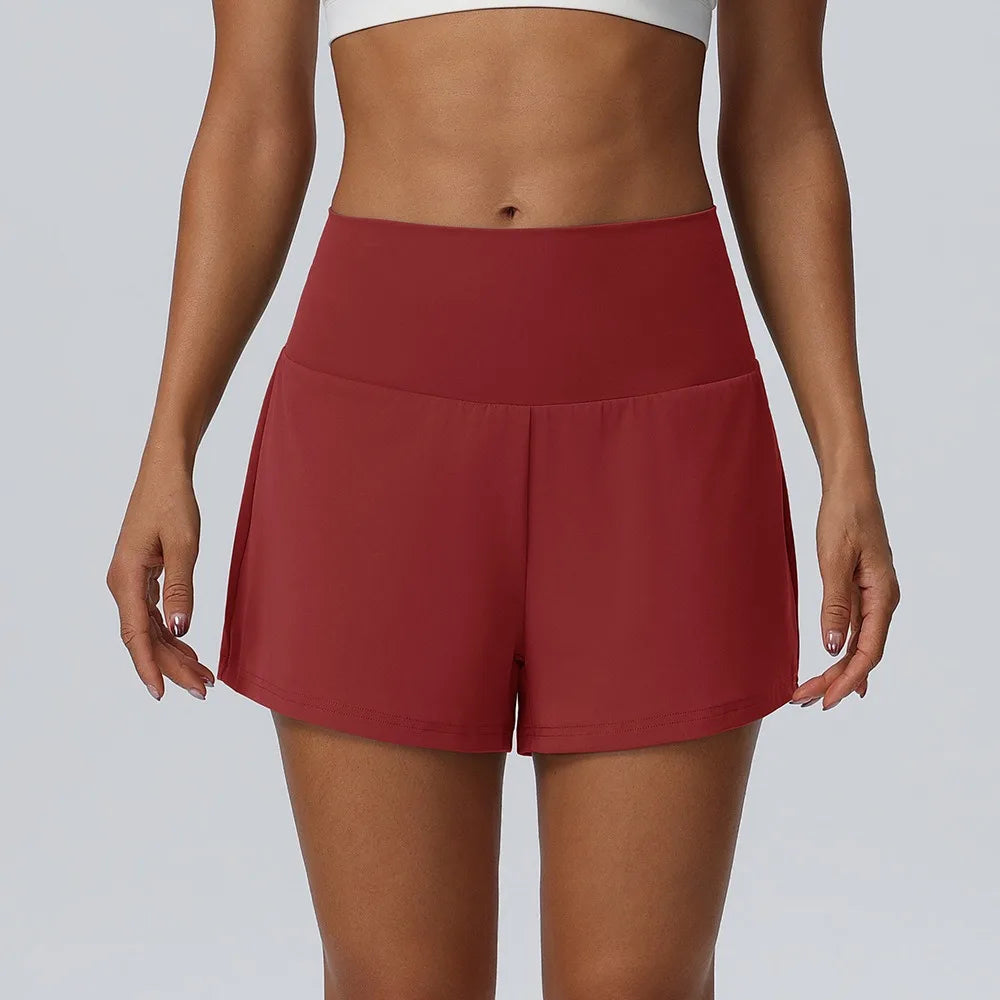 Eine Frau trägt dunkelrote, schnelltrocknende Sportshorts und ein weißes Sport-BH.