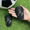 A hand holds a black mini wear-resistant shin guard for soccer, showing a stick figure running pose.