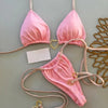 A pink halter bikini set displayed against a light gray wall.