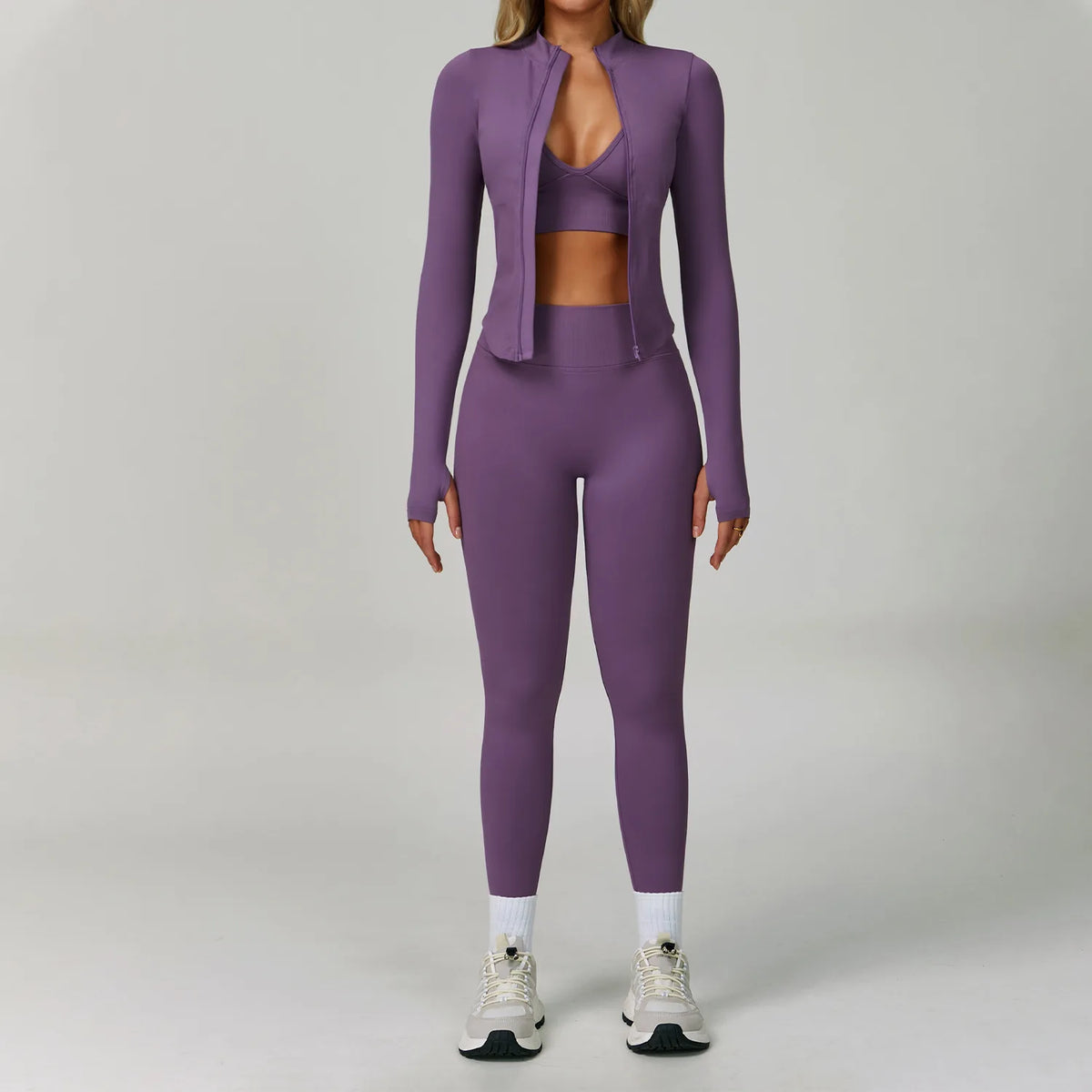 Eine Frau trägt ein nahtloses lila Sport-Yoga-Set mit langärmeligem Zip-Top und passenden Leggings.