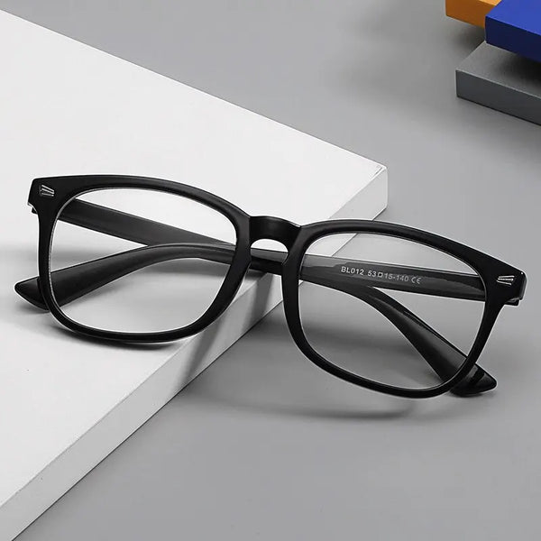 A pair of black reading glasses with dark frames and clear lenses resting on a white surface.